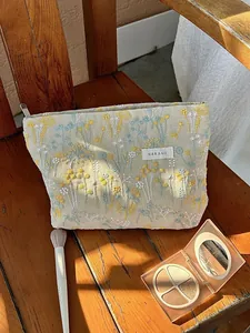 Detailed macro view of vintage floral embroidery on a beige linen makeup storage bag