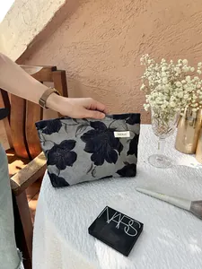 Close-up of elegant floral embroidery makeup bag on a table with cosmetics accessories