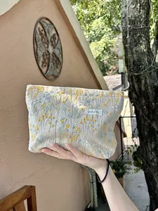 Close-up of elegant floral embroidery on a portable beige canvas makeup storage pouch