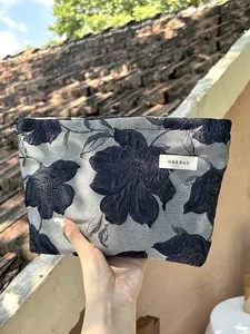 Close-up detail of the floral embroidered cosmetic bag showing premium relief texture