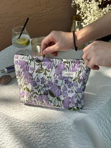 Detailed shot of hands opening a premium lilac floral embroidered makeup storage pouch