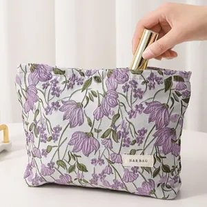 Close-up of floral embroidered cosmetic bag showing purple flowers and fabric texture