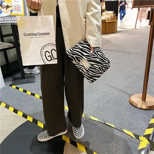 Stylish zebra print clutch makeup bag shown in a realistic lifestyle shopping mall setting.