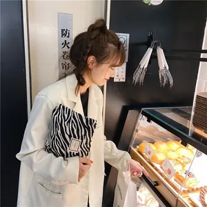 Chic zebra pattern makeup bag held by a model in a cozy bakery lifestyle setting