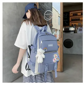 Primo piano di uno zaino blu per la scuola con ciondolo a forma di orsetto e badge