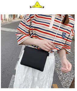 Primo piano di una borsa a tracolla in tela nera minimalista indossata da una modella
