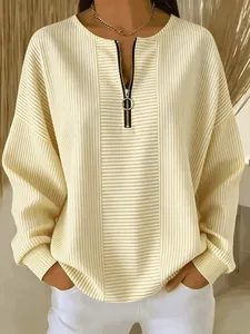 Dettaglio della maglia a righe color crema con cerniera ad anello e spalle scese.