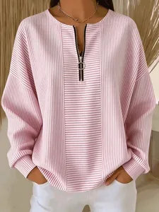 Dettaglio di una maglia a maniche lunghe a righe rosa con zip e spalle scese, stile casual.