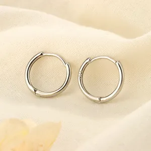 Detalle macro de pendientes de aro minimalistas de plata de ley S925 sobre tela