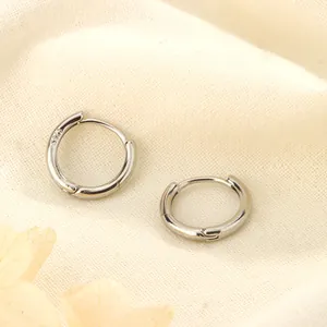 Primer plano que muestra la marca S925 en aretes de aro minimalistas de plata sobre tela
