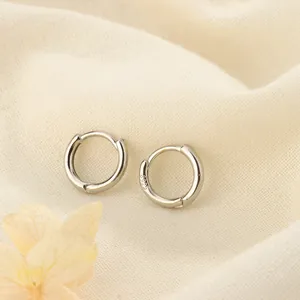 Primer plano de aros minimalistas de plata de ley S925 sobre una tela suave con textura