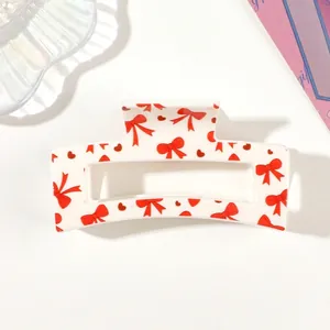 Detailed close-up view of a white hair claw clip with red bow and heart patterns