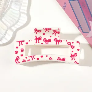 Close-up of a white shark clip featuring pink heart and bowknot heat transfer prints.