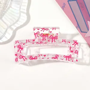 Macro view of transparent acrylic hair claw clip with pink heart and bow patterns