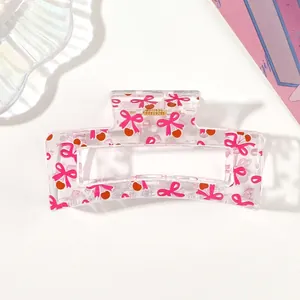 Close-up of transparent hair claw clip featuring pink bow and cherry pattern detail