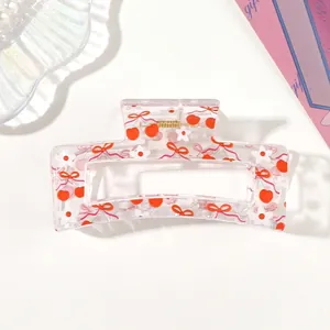 Detailed view of transparent acrylic hair claw clip featuring cherry and flower print patterns