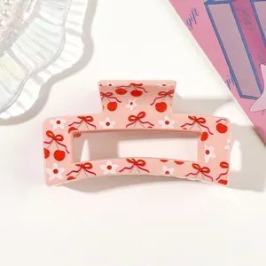 Macro view of pink hair claw clip with delicate cherry, bow and flower prints