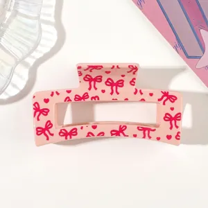 Close-up of a pink hair claw clip featuring cute bow and heart patterns for women.