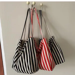 Detailansicht großer gestreifter Canvas-Tragetaschen in Rot und Schwarz an der Wand