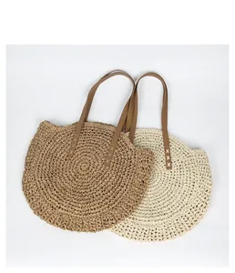 Two bohemian round straw bags in natural and cream woven textures with brown straps