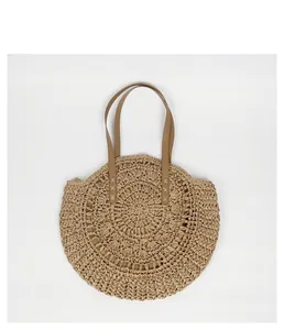 Front view of bohemian round straw woven bag with brown shoulder straps on white