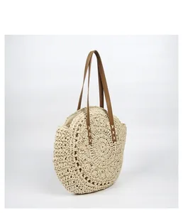 Bohemian round straw woven shoulder bag with tan leather straps on a clean white background
