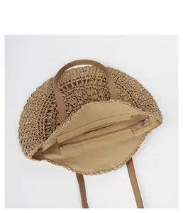 Detail of the woven straw beach bag showing internal zipper pocket and tan lining.