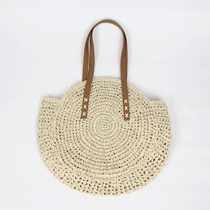 Handwoven circular straw beach tote bag with durable brown faux leather shoulder straps