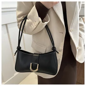 Chic black underarm baguette bag featuring a gold U-shaped buckle and minimalist design