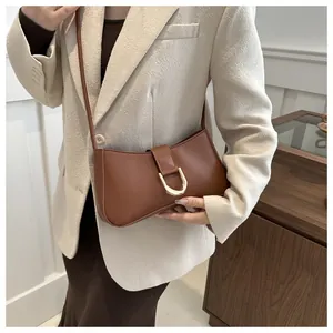 Chic brown faux leather underarm bag with gold D-buckle shown on model