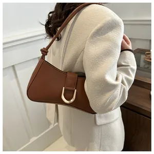 Close-up detail view of a chic brown leather underarm bag with elegant gold horseshoe buckle