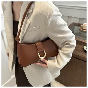 A detailed view showing a chic brown leather underarm bag with a gold U-shaped buckle