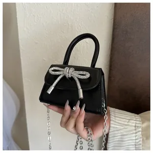 Vista detallada del mini bolso negro con elegante lazo de strass plateado y cadena