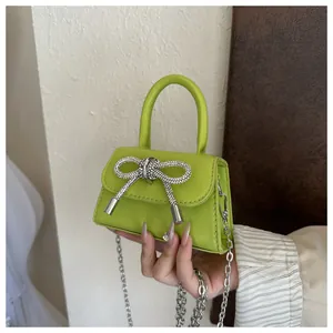 Mini bolso de mano verde lima con lazo de cristal brillante y cadena de plata.