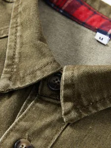 Detaillierte Nahaufnahme eines olivgrünen Denim-Arbeitshemd-Kragens und Knöpfen