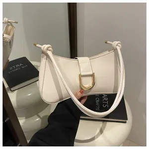 Close-up of a white French chic underarm bag with a golden D-ring buckle and knotted strap.