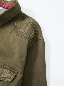 Nahaufnahme der beanspruchten Schulter und des karierten Kragenfutters am olivgrünen Jeanshemd