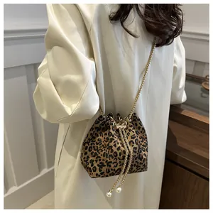 Detalle de bolso saco de leopardo con cadena dorada y cordones con perlas