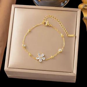Elegante pulsera de acero de titanio dorado con un delicado colgante de flor de circonita
