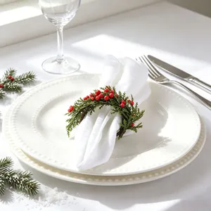 Handmade Christmas berry wreath napkin ring with green pine needles on white plate