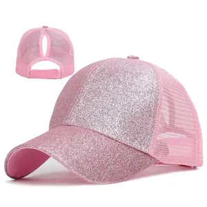 Dettaglio della texture glitterata di un cappello rosa con apertura per coda di cavallo.