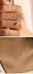 Detalle de un collar delicado con corazón de oro y circonita redonda usado por una modelo