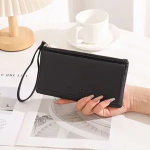 Detail of a minimalist black long leather wallet for women with embossed logo and strap