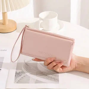 Close-up view of a pink minimalist long wallet for women with wrist strap and zipper