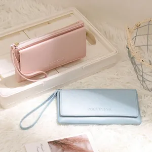Detail view of stylish long wallets with wrist straps in pink and blue faux leather.