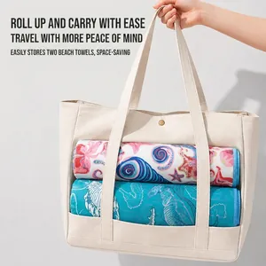 Serviettes de plage en microfibre imprimées rangées dans un grand sac fourre-tout blanc.