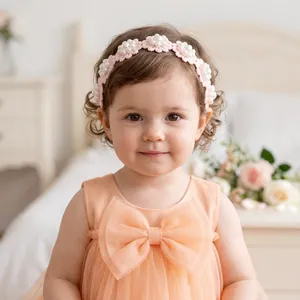 Detail of a sweet toddler girl wearing a pink floral lace headband with pearls