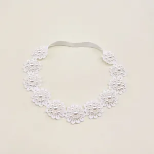 Detail view of a white lace children's headband with exquisite pearl flower accents
