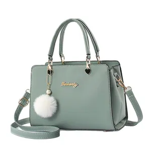 Elegant sage green women's handbag featuring a top handle and a fuzzy white pom-pom charm