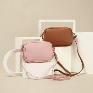 Set of two minimalist PU leather crossbody bags in pink and brown on white geometric props.